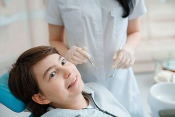 Obraz na płótnie Canvas Patient in dental chair. Teen boy having dental treatment at dentist's office. Healthy teeth, dental care concept.