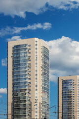 Fototapeta premium Two multi-storey buildings with glazed balconies. Summer sunny day and blue sky with white clouds.