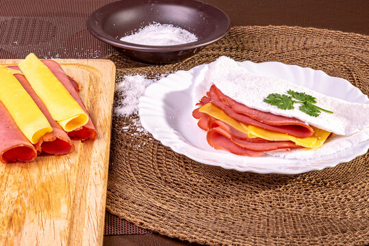 Tapioca beiju with ham, cheese and bologna on a plate on the table.