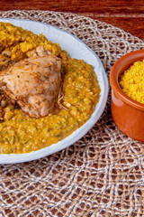 Delicious Caruru. Traditional Afro-Brazilian dish made with okra and dried shrimp, accompanied by vatapa, beans, rice, chicken and farofa. On a wooden table.