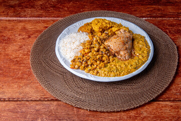 Delicious Caruru. Traditional Afro-Brazilian dish made with okra and dried shrimp, accompanied by vatapa, beans, rice, chicken and farofa. On a wooden table.