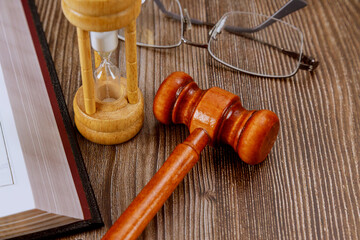 Open law book with a wooden judge's gavel on table in a courtroom or law enforcement office.