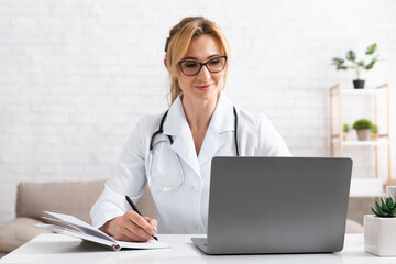 Patient talk with doctor using video call on laptop. Woman in white coat make notes in notebook