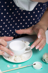 Roses with petals made of white polymer clay. A woman sticks them on a mug. Crafts from polymer clay.