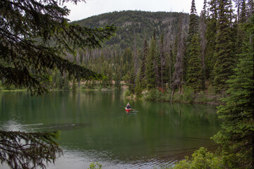 Fototapeta na wymiar Canoeing on a green lake surrounded with mountains