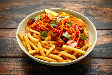 Loaded French Vegan Fries with tofu, pickled vegetables radish, carrot and spicy hot sauce. healthy food on wooden rustic table.