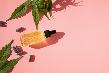 Hemp oil and cannabis leaves on pink background