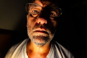 White adult man with reading glasses. Man looking straight into camera.