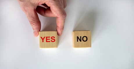 Hand making a choice between two cubes with Yes and No on white background. Business concept. Copy space.