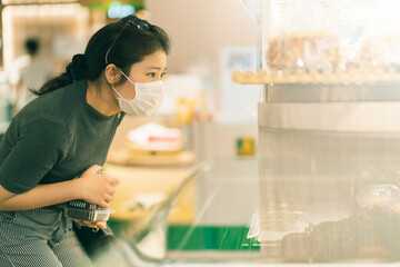 new normal after covid epidemic young smart asian female shopping new lifestyle in supermarket with face shild or mask protection hand choose fresh vegetable of fruit new normal lifestyle