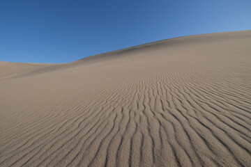 low angle of wide sand dune under blue sky. at Dunhuang, Gansu province, China