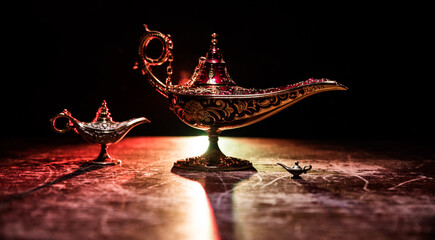 Lamp of wishes concept. Antique Aladdin arabian nights genie style oil lamp with soft light white...