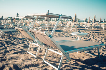 Neatly arranged sunbeds in a famous beach in the Riviera Romagnola area, on the Adriatic Coast....