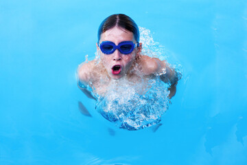 Naklejka premium Little boy athlete swims in the pool by the crawl. The concept of training and children's sports