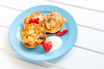 Healthy breakfast concept. Close up cottage cheese pancakes with fresh blueberries and on white woodene background.