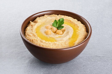 Chickpeas hummus with olive oil and parsley on a gray background.