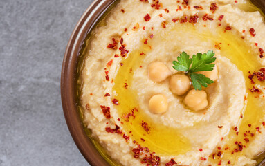 Chickpeas hummus with olive oil, paprika and parsley on a gray background.