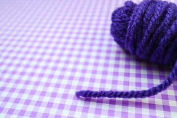 Purple yarn ball on a purple checkered background. 