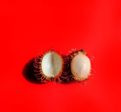Rambutan fruit cut in half with red background. exotic fruits from Asia