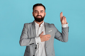 Portrait of millennial businessman taking oath on blue background