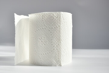 A roll of white toilet paper on a gray background. Soft hygienic toilet paper on a light background
