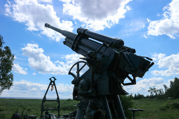 old anti-aircraft gun on cloudy sky background