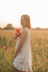 Portrait of a beautiful girl holding a bouquet of poppies in a poppy field