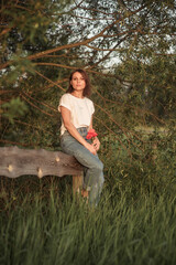 Girls in jeans sits on cut tree