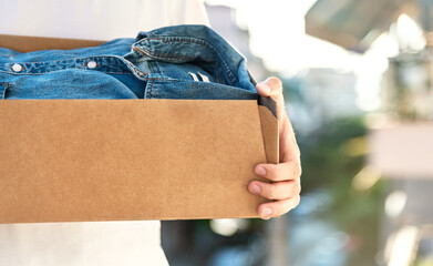 Man holding cardboard box with clothes inside. Concept donation and reuse or recycle your used...