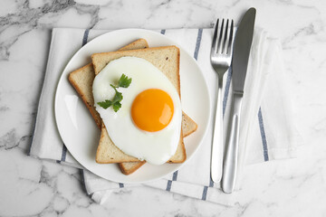 Tasty fried egg with bread on white marble table, flat lay