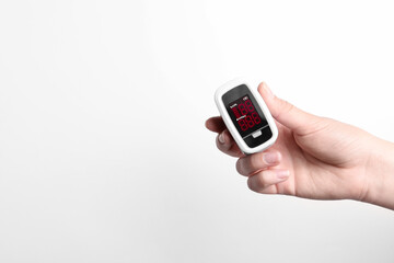 Woman holding fingertip pulse oximeter on white background, closeup. Space for text