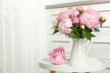 Bouquet of beautiful peonies in vase on white table. Space for text