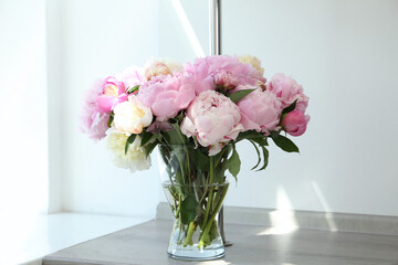 Bouquet of beautiful peonies in vase on wooden table
