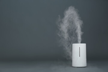 Modern air humidifier on grey background. Space for text