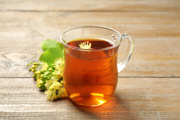 Cup of tea and linden blossom on wooden table