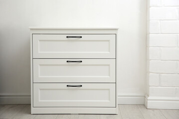 Modern white chest of drawers near light wall in room. Interior design