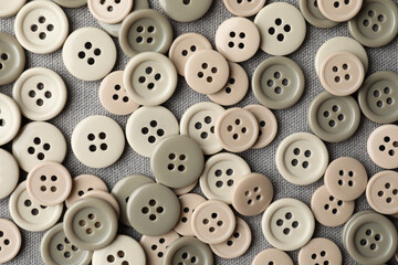 Obraz premium Many plastic sewing buttons on grey fabric, flat lay