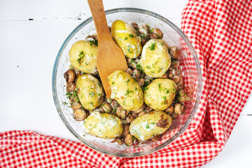 Roasted young potatoes in glass baking dish with mushrooms.