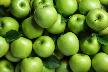 Pile of tasty green apples with leaves as background, top view - Powered by Adobe