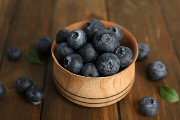 Fresh ripe blueberries in bowl on wooden table