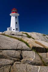 Fototapeta na wymiar Peggys Cove lighthouse on smooth granite rocks against a blue sky Nova Scotia