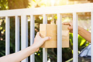 Hands of delivery man or postman carry the goods package and sent to receiver at home,Delivery man holding boxes person who sent the package box to the recipient to arrive at home