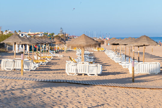 Sun umbrellas and hammocks in row for rent for tourist in Islantilla beach