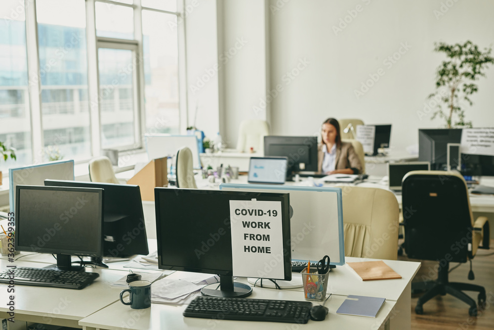 Aufkleber paper with announcement about work from home on one of computer monitors