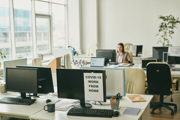 Paper with announcement about work from home on one of computer monitors