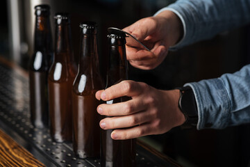 Beer competition. Bartender with clock, opens bottles of beer on wooden bar counter