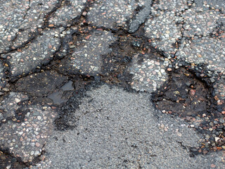 Damaged Broken city asphalt road with a lot of pits. Depressive urban landscape. bad road.
