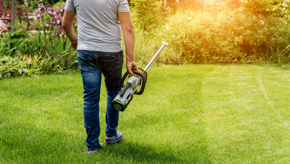 A gardener trimming trees with hedge trimmer