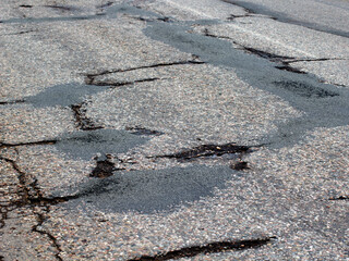 Damaged Broken city asphalt road with a lot of pits. Depressive urban landscape. bad road.