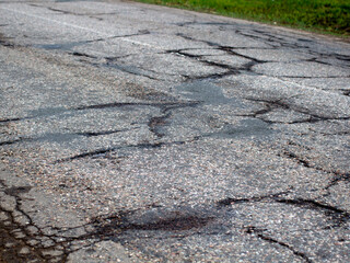 Damaged Broken city asphalt road with a lot of pits. Depressive urban landscape. bad road.